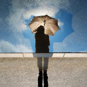 Person standing on a grey surface while holding an umbrella
